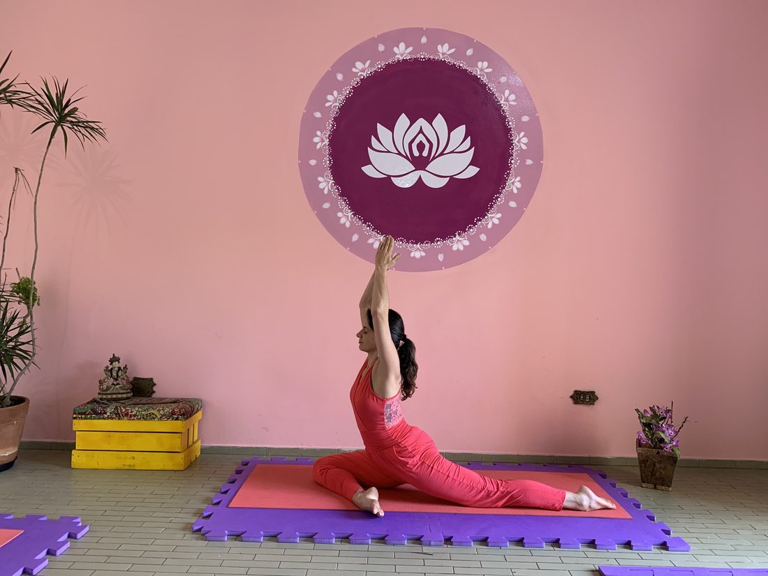 Aluna em postura de yoga diante da mandala de lótus da parede