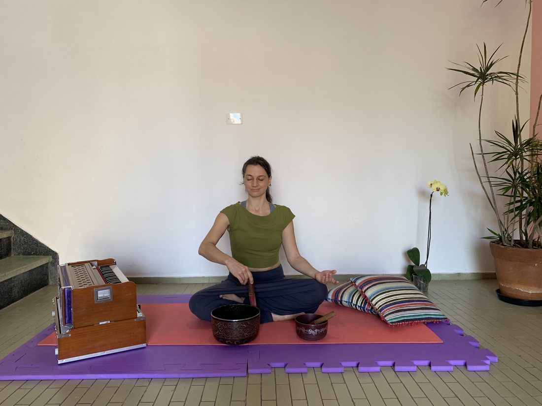 Instrutora sentada com harmônio e tigela tibetana