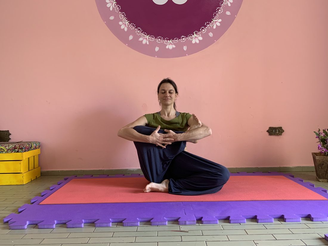 Instrutora sentada em meditação sobre o tapete